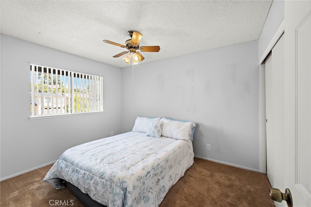 carpeted bedroom featuring a closet, a textured ceiling, baseboards, and ceiling fan