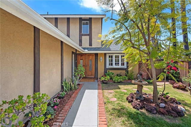 doorway to property featuring stucco siding and fence