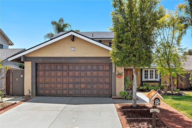 ranch-style home with an attached garage, stucco siding, fence, and concrete driveway