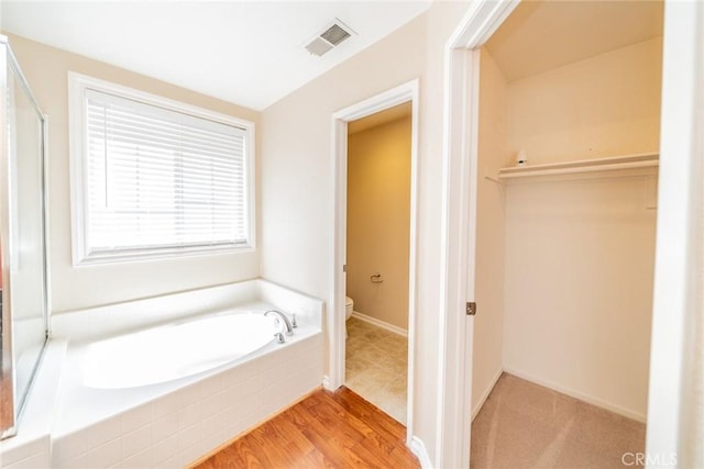 32674 Clearvail Dr, Temecula, CA 92592 - bathroom with toilet, a garden tub, a spacious closet, baseboards, and wood finished floors