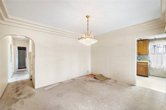 unfurnished dining area with arched walkways, a chandelier, and light colored carpet