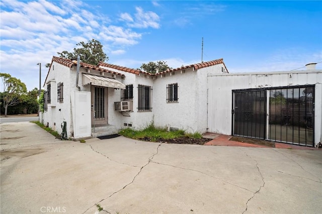 back of house featuring stucco siding, cooling unit, and a tile roof