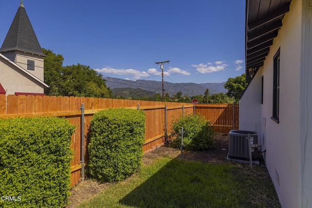 view of yard featuring central AC unit, a mountain view, and a fenced backyard