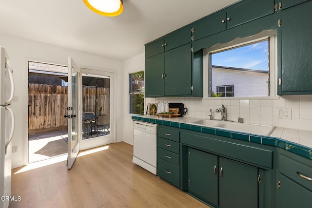 kitchen featuring decorative backsplash, french doors, a sink, light wood finished floors, and dishwasher