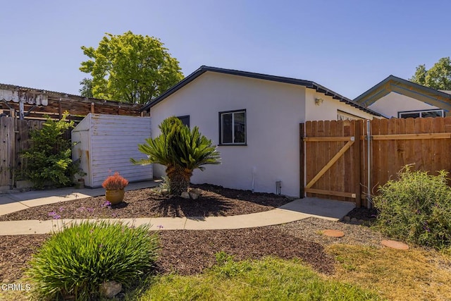 view of property exterior featuring fence, a gate, and stucco siding