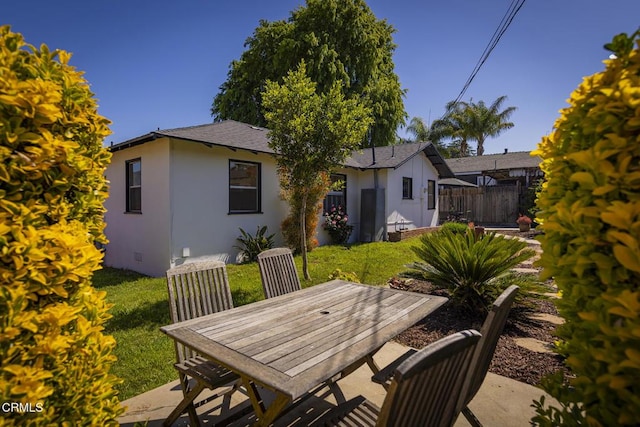 exterior space with a lawn, fence, a patio, outdoor dining space, and stucco siding