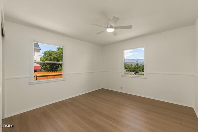 spare room with a ceiling fan, baseboards, and wood finished floors