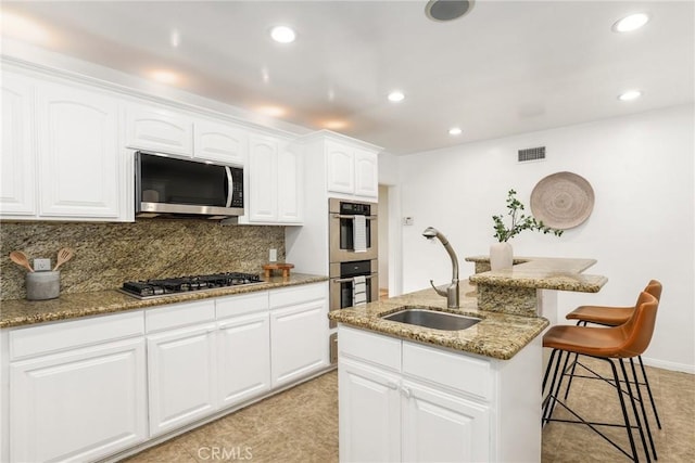 8163 Billowvista Dr, Playa Del Rey, CA 90293 - kitchen featuring visible vents, a breakfast bar, light stone counters, a sink, and stainless steel appliances