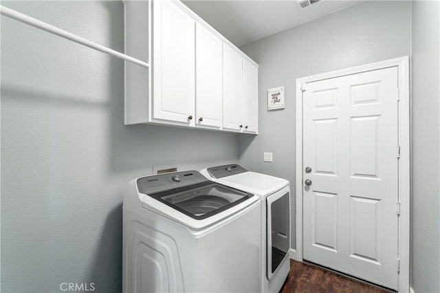 laundry area featuring independent washer and dryer, cabinet space, and dark wood-type flooring