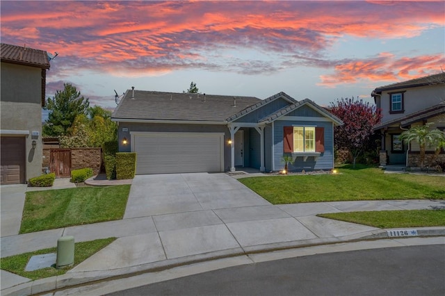 view of front facade with a lawn, a tiled roof, an attached garage, and driveway