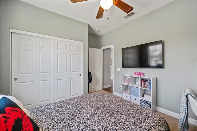 bedroom featuring a ceiling fan, visible vents, wood finished floors, baseboards, and a closet