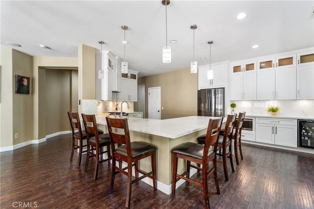 kitchen with dark wood-style flooring, appliances with stainless steel finishes, beverage cooler, a peninsula, and decorative backsplash