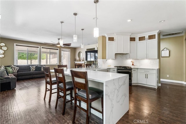 kitchen featuring a breakfast bar area, gas range, a sink, a peninsula, and open floor plan