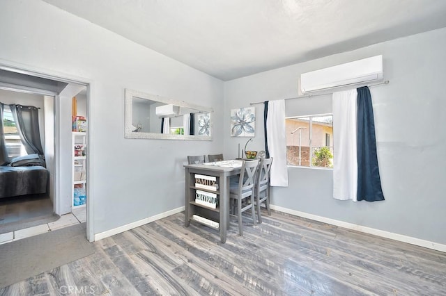 dining room featuring plenty of natural light, baseboards, a wall mounted AC, and wood finished floors