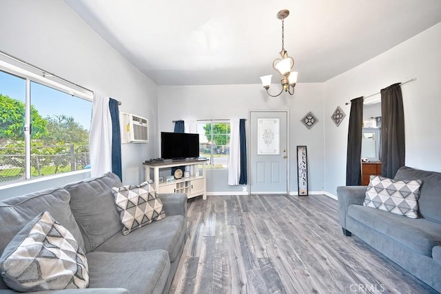 living area with baseboards, a wall mounted AC, wood finished floors, and a chandelier