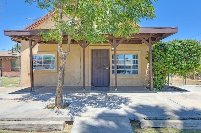 entrance to property featuring fence and stucco siding