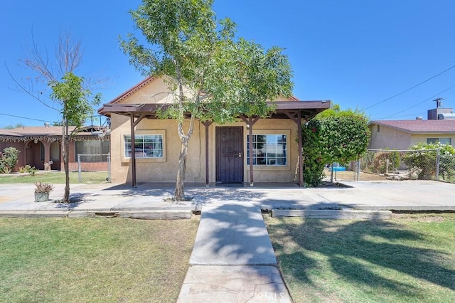 view of front of home with a front lawn, stucco siding, and fence