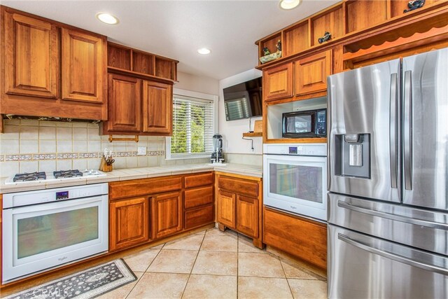 6377 Sugar Pines Cir, Angelus Oaks, CA 92305 - kitchen with white appliances, brown cabinets, open shelves, light tile patterned floors, and decorative backsplash