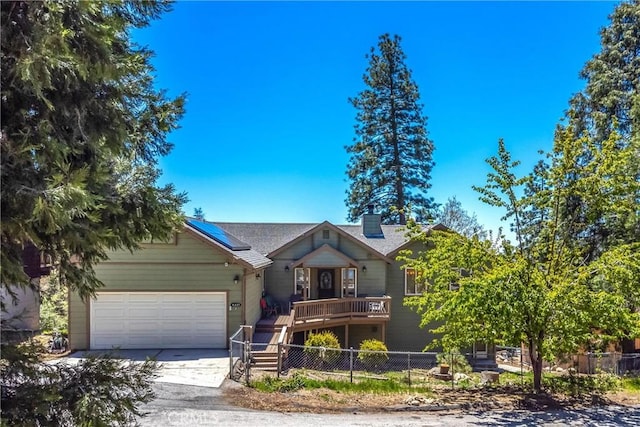 6377 Sugar Pines Cir, Angelus Oaks, CA 92305 - view of front of home with fence, concrete driveway, an attached garage, a chimney, and roof mounted solar panels