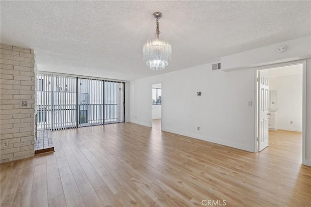 10966 Rochester Ave Unit 5D, Los Angeles, CA 90024 - unfurnished living room featuring a textured ceiling, an inviting chandelier, visible vents, and light wood-style floors