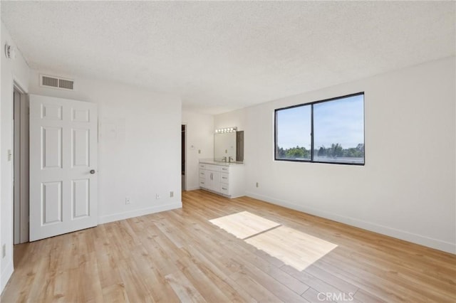 10966 Rochester Ave Unit 5D, Los Angeles, CA 90024 - unfurnished bedroom featuring light wood finished floors, a textured ceiling, baseboards, and visible vents