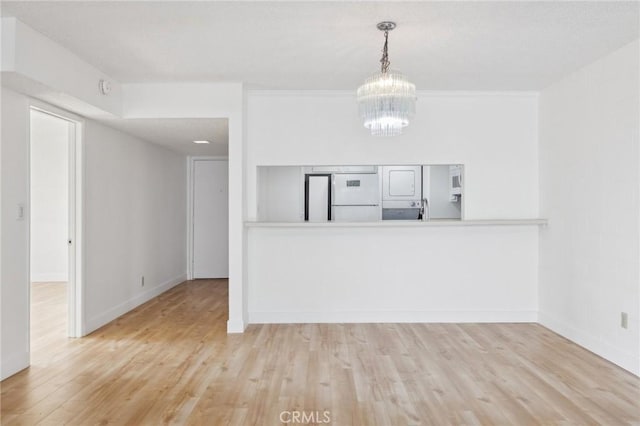 10966 Rochester Ave Unit 5D, Los Angeles, CA 90024 - unfurnished living room with baseboards, a notable chandelier, and wood finished floors