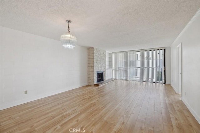 10966 Rochester Ave Unit 5D, Los Angeles, CA 90024 - unfurnished living room featuring a fireplace, a textured ceiling, light wood-type flooring, baseboards, and a chandelier