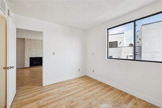 10966 Rochester Ave Unit 5D, Los Angeles, CA 90024 - spare room featuring baseboards, a fireplace, a textured ceiling, and wood finished floors