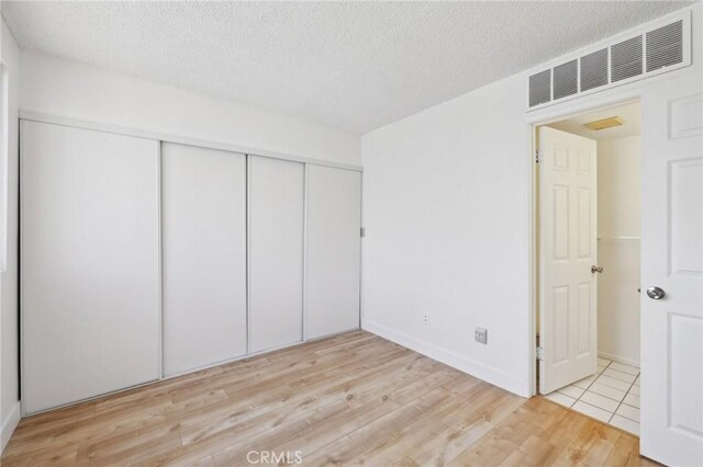 10966 Rochester Ave Unit 5D, Los Angeles, CA 90024 - unfurnished bedroom with a textured ceiling, visible vents, wood finished floors, baseboards, and a closet