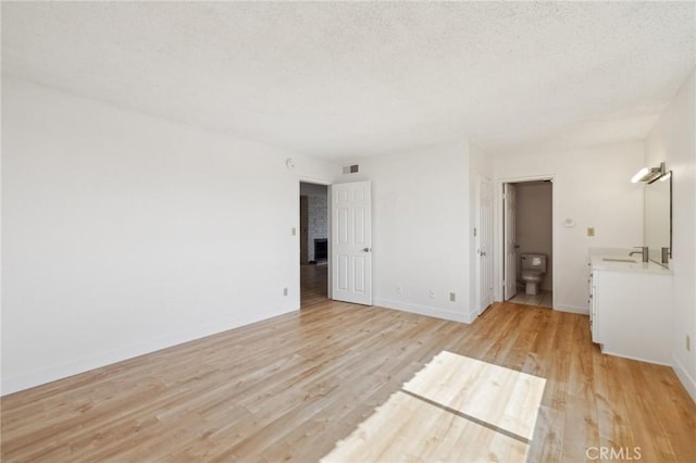 10966 Rochester Ave Unit 5D, Los Angeles, CA 90024 - unfurnished bedroom featuring a textured ceiling, visible vents, light wood-type flooring, a sink, and baseboards