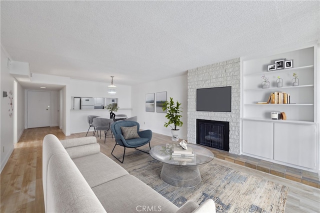 10966 Rochester Ave Unit 5D, Los Angeles, CA 90024 - living room featuring a textured ceiling, built in features, wood finished floors, and a fireplace