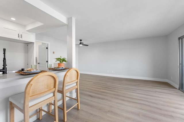kitchen featuring baseboards, ceiling fan, light wood-style flooring, and white cabinets