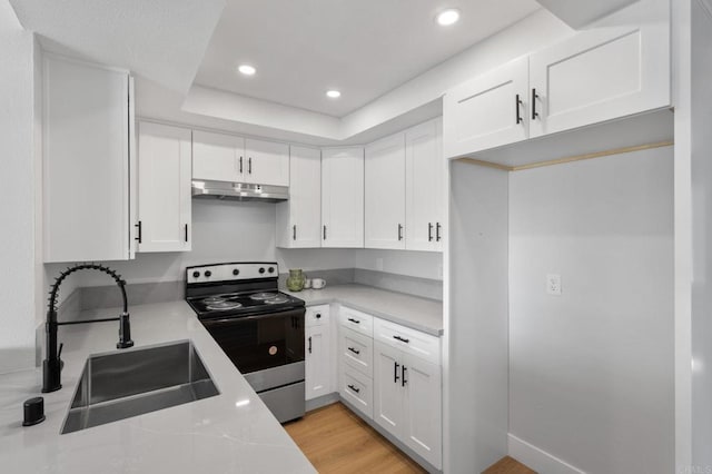 kitchen with stainless steel range with electric cooktop, a sink, light countertops, white cabinets, and under cabinet range hood