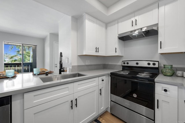 kitchen with light countertops, a sink, under cabinet range hood, and stainless steel electric range oven