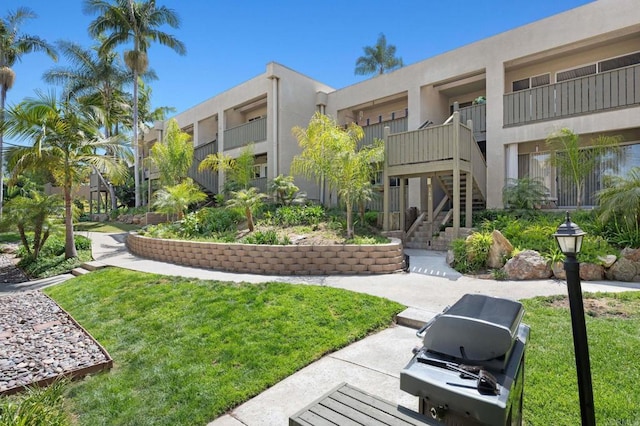 view of community featuring a lawn and stairs