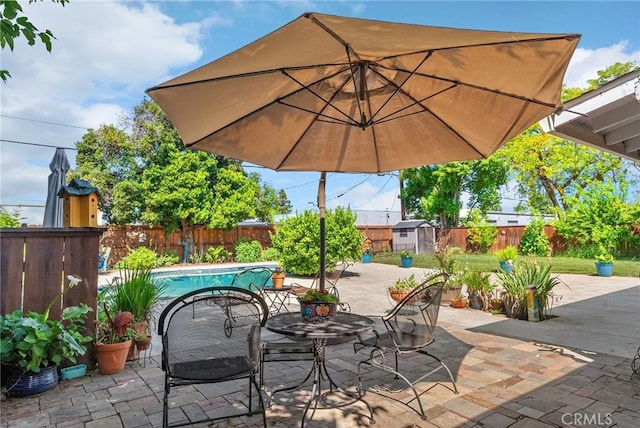 view of patio / terrace featuring an outdoor structure, a fenced backyard, a fenced in pool, a storage shed, and outdoor dining space