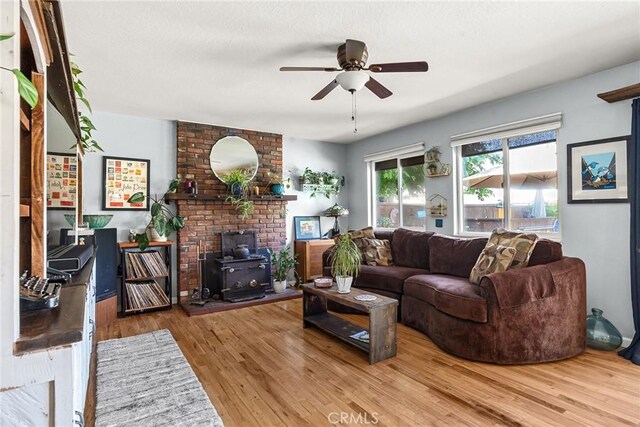 living area featuring a ceiling fan, wood finished floors, and a wood stove