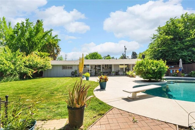 back of house with a lawn, a patio, board and batten siding, and an outdoor pool