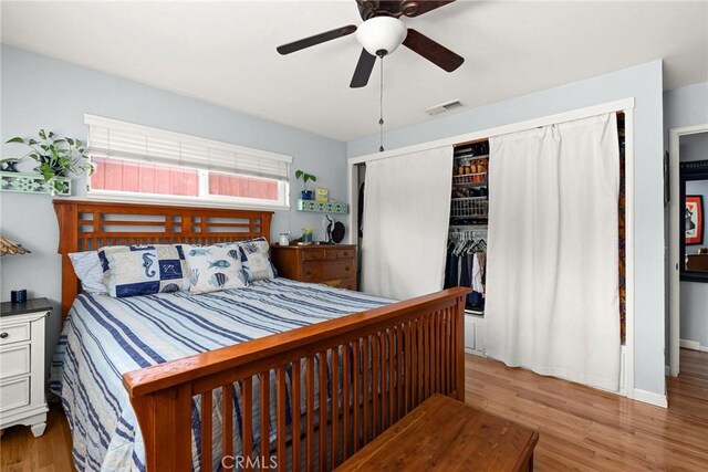 bedroom with visible vents, a ceiling fan, wood finished floors, and a closet