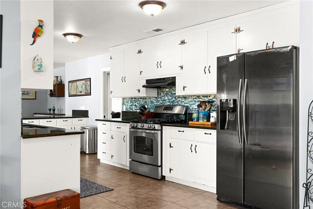 kitchen featuring visible vents, dark countertops, stainless steel range with gas cooktop, refrigerator with ice dispenser, and under cabinet range hood