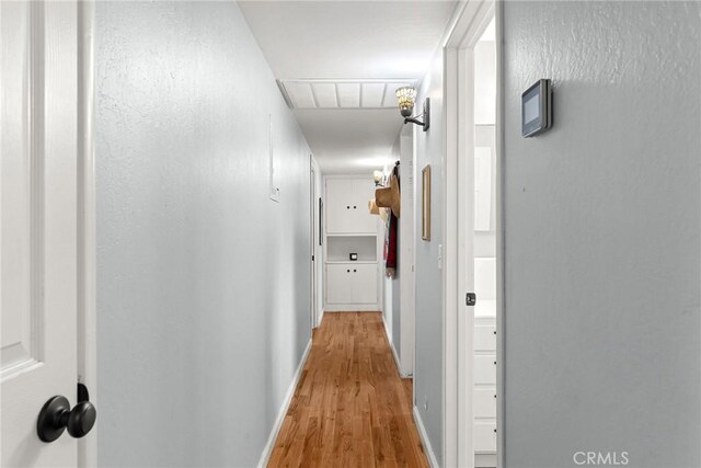 corridor featuring baseboards, visible vents, and light wood-style floors