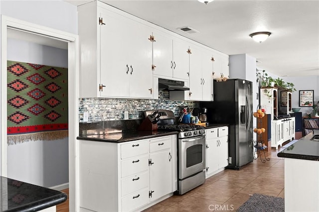 kitchen with visible vents, dark countertops, under cabinet range hood, backsplash, and stainless steel appliances