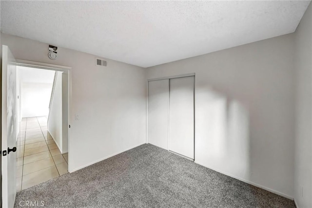 interior space with a textured ceiling, visible vents, baseboards, and tile patterned floors