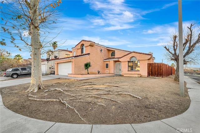 view of front facade featuring fence, stucco siding, a tiled roof, an attached garage, and driveway