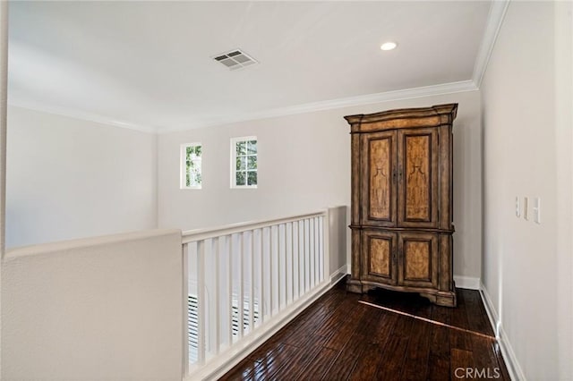 hallway featuring visible vents, dark wood finished floors, baseboards, ornamental molding, and recessed lighting