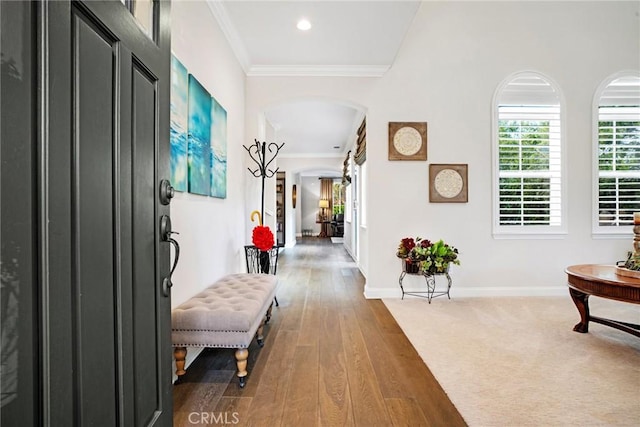 hall featuring arched walkways, recessed lighting, baseboards, wood finished floors, and ornamental molding