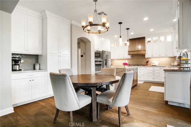 dining area with visible vents, dark wood-style floors, recessed lighting, arched walkways, and a notable chandelier
