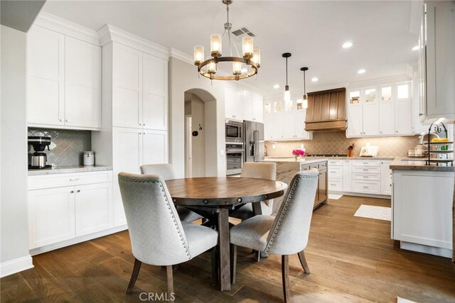26238 Beecher Ln, Stevenson Ranch, CA 91381 - dining area with arched walkways, a chandelier, recessed lighting, and dark wood-style floors