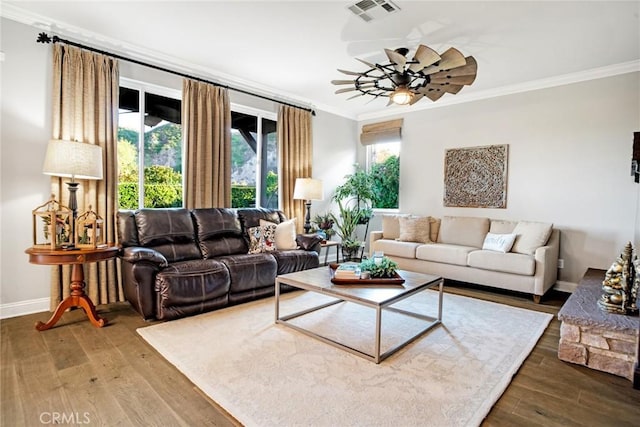 living room featuring visible vents, ornamental molding, wood finished floors, baseboards, and a ceiling fan