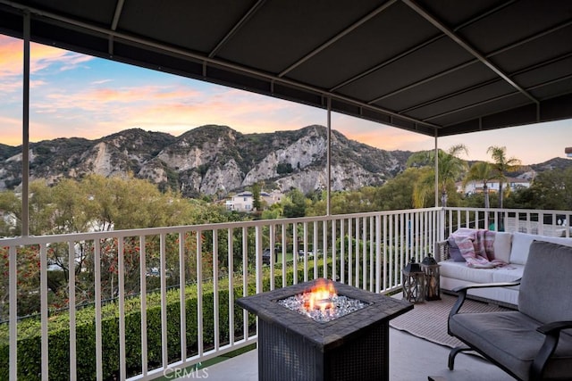 balcony at dusk with an outdoor living space with a fire pit and a mountain view